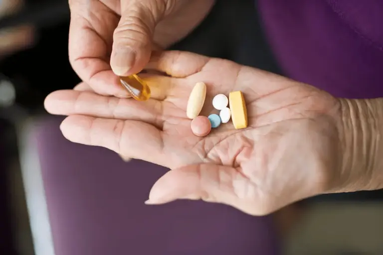 An elderly woman picking pills on her hand