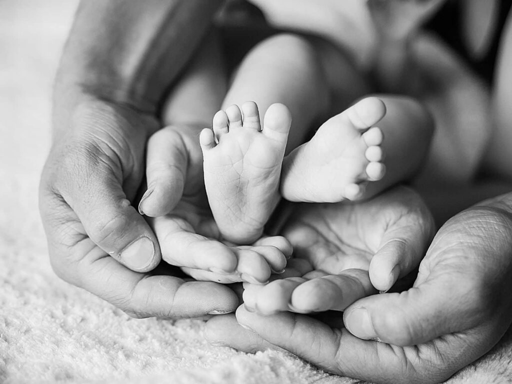 black and white image of parents holding hands as well as their child