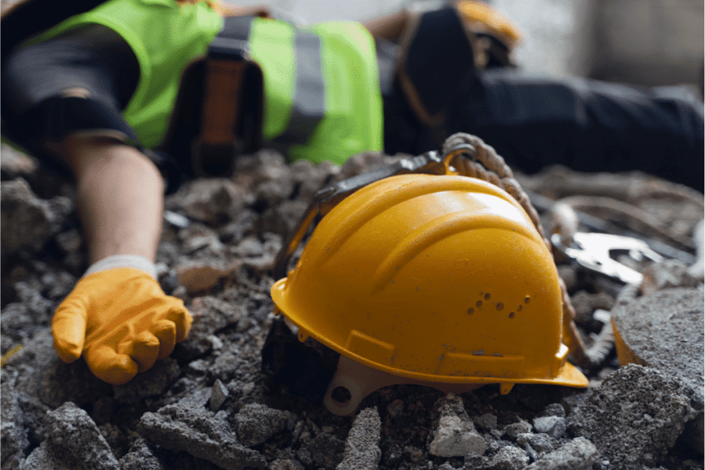 A man lying down unconcious with his hard hat on the rocks