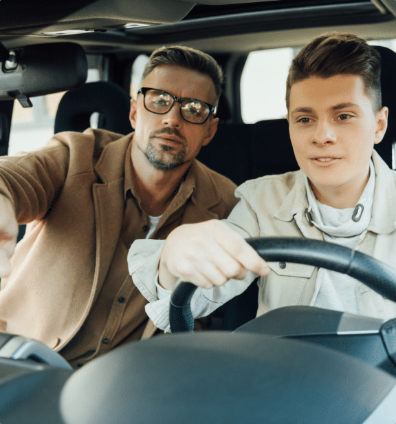 A man teaching a teenage how to drive