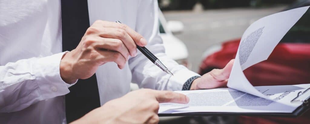 A man holding a clipboard of insurance information following a car accident settlement process